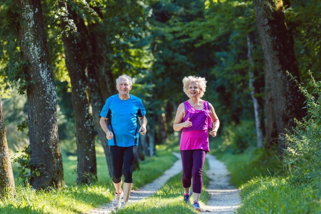 aging adult couple jogging in woods for stamina